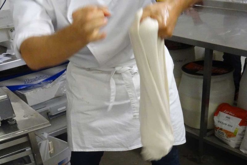 petrissage de la pate a pizza Personne pétrissant de la pâte à la main dans une cuisine professionnelle.