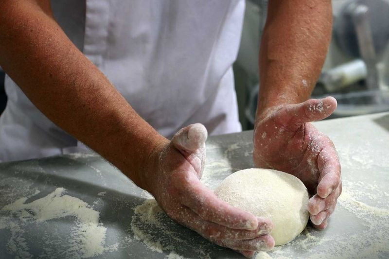 technique de panification Mains pétrissant une boule de pâte sur une surface farinée.